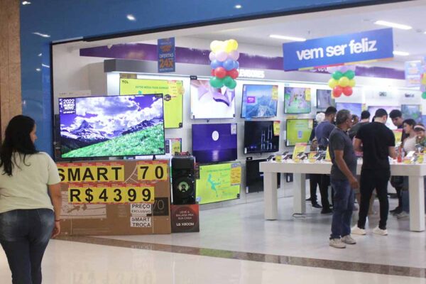 11. Middle class families at the shopping mall look at TVs on promotion at the same electronics store that has a branch in Uruguaiana market. “Come to be happy,” says the banner. Rio de Janeiro, Brazil, 2022.